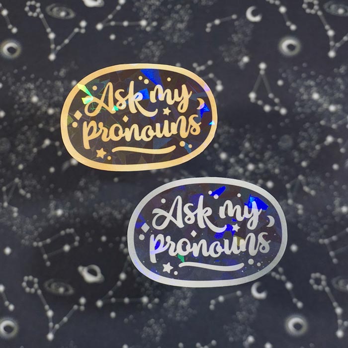 two ask my pronouns stickers on a dark background with stars by atelier persephone