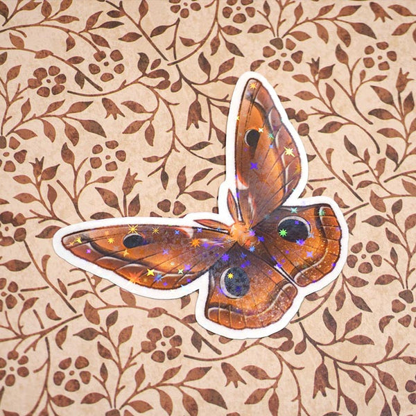 waning crescent moon moth holo sticker on a leaf paper background from atelier persephone